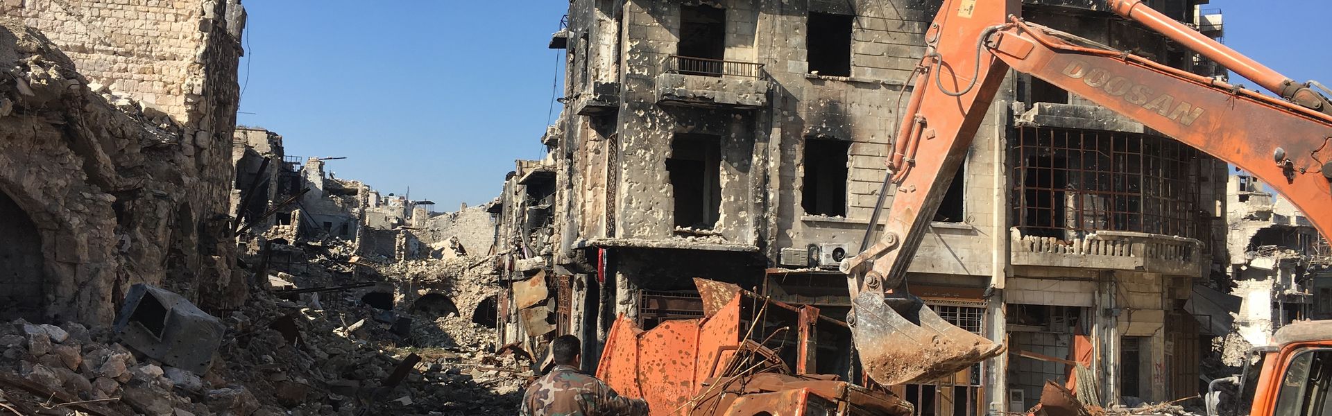 An excavator removes debris from a destroyed vehicle near the Umayyad Mosque in Aleppo