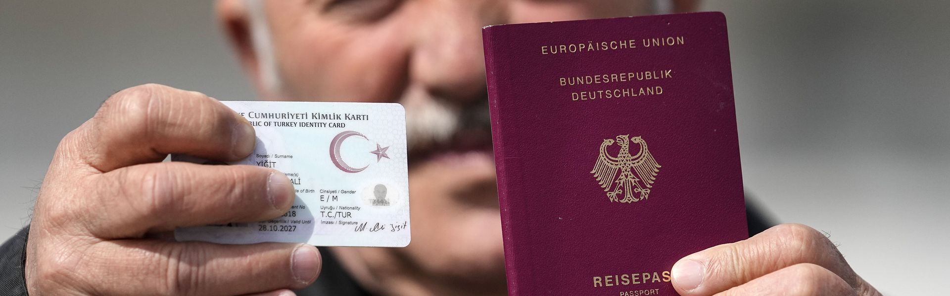 Mehmet Ali Yigit, who has been living in Germany for more than 50 years, shows his German passport and Turkish ID after he voted at the Gruga Hall in Essen, Germany.