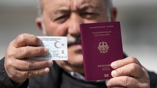 Mehmet Ali Yigit, who has been living in Germany for more than 50 years, shows his German passport and Turkish ID after he voted at the Gruga Hall in Essen, Germany.