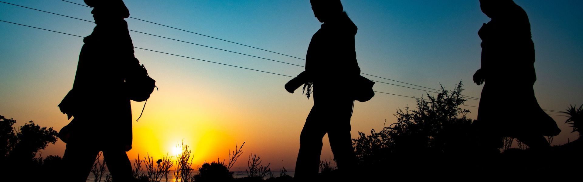 Silhouettes Of Walking Refugees In The Dawn.